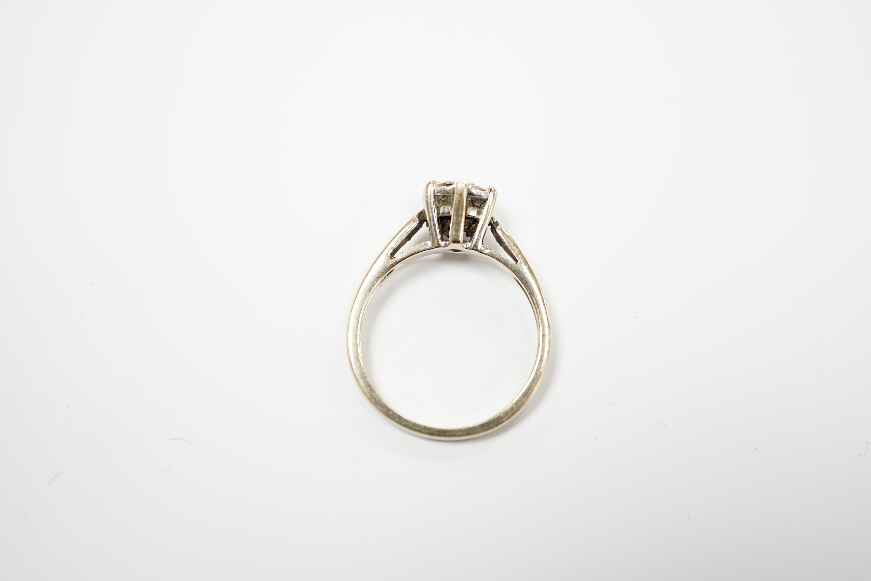 A 750 white metal and seven stone diamond set circular cluster ring, size M, gross weight 3.2 grams.